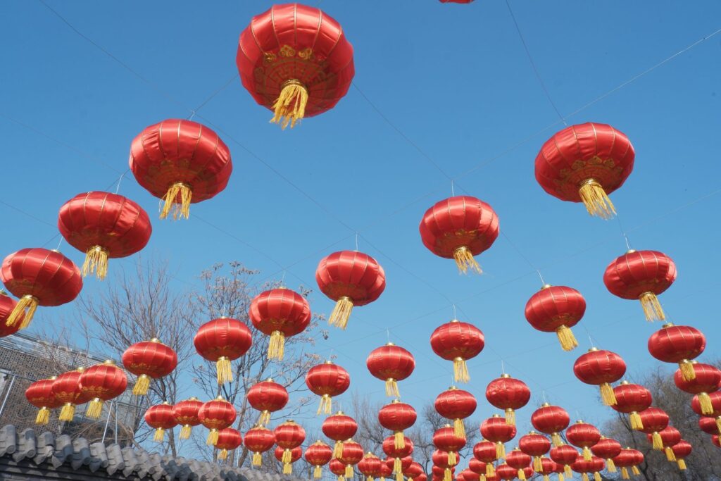 Vibrant red lanterns hanging outdoors against clear blue sky, symbolizing festive celebration.