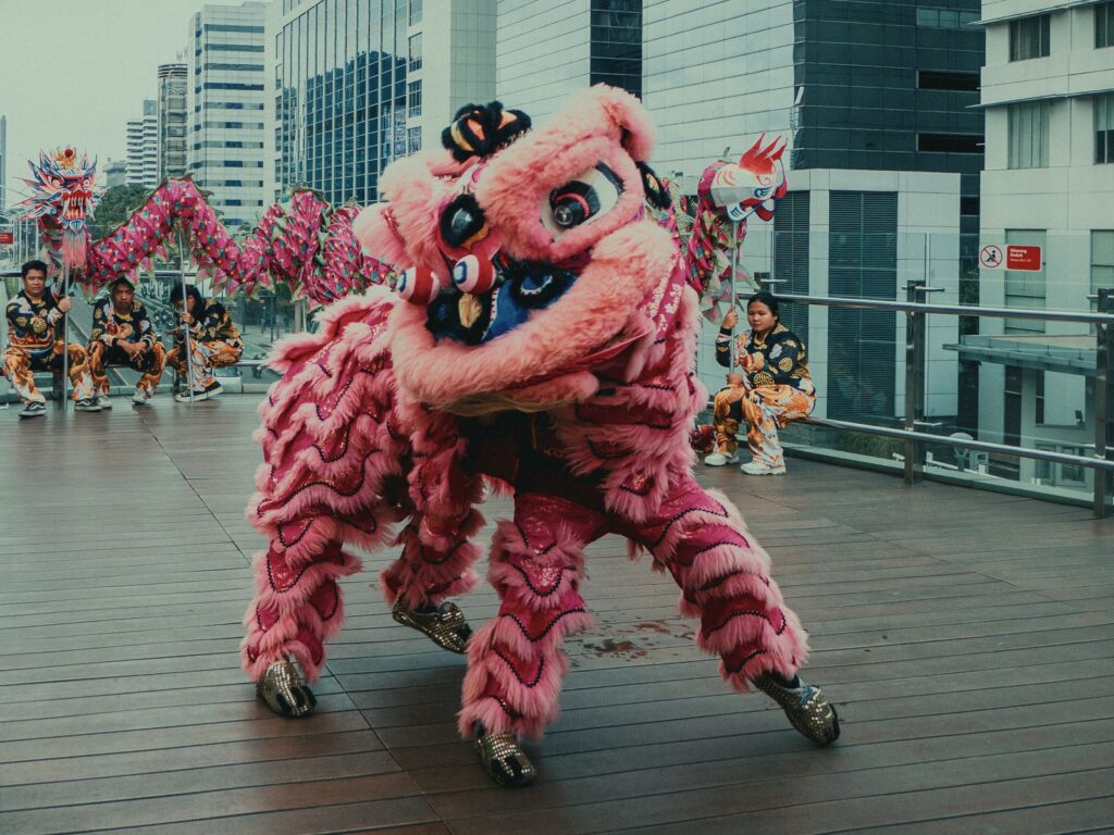 Colorful traditional Chinese lion dance performance on a Jakarta rooftop with city skyline backdrop.