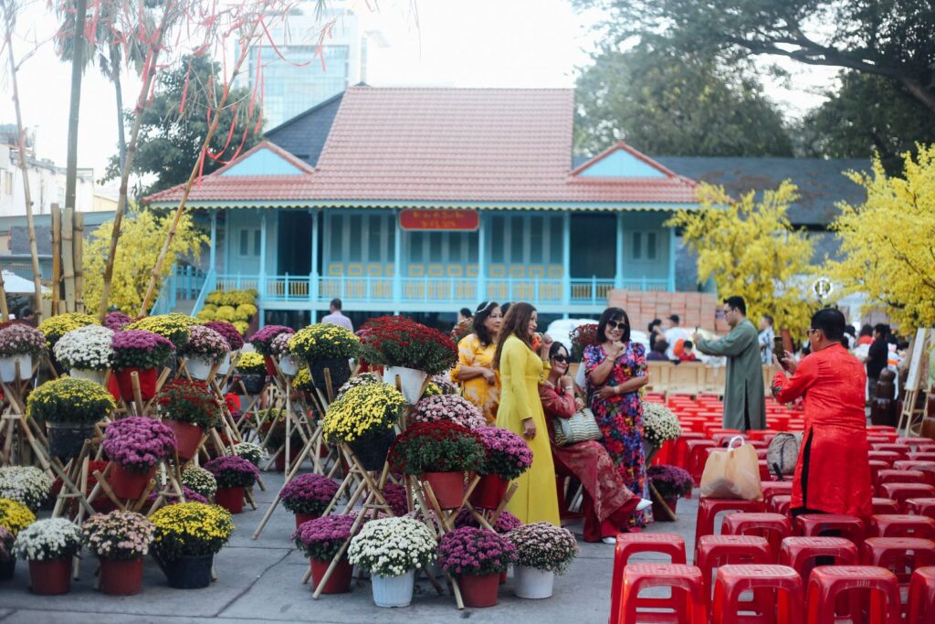 Colorful Tet festival scene with people in traditional attire and vibrant flowers, capturing cultural celebration.